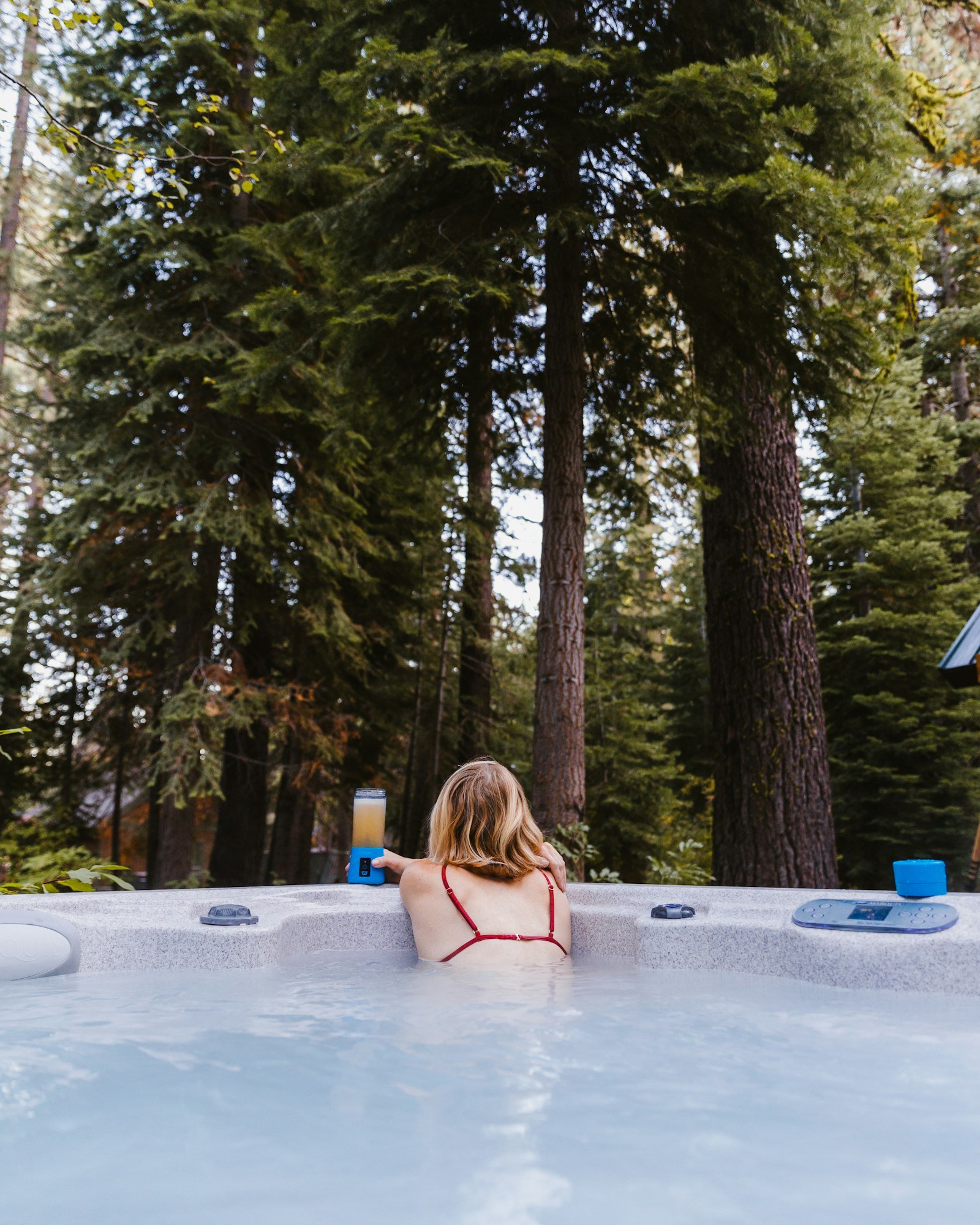 Mujer en un jacuzzi de exterior rodeado de bosque